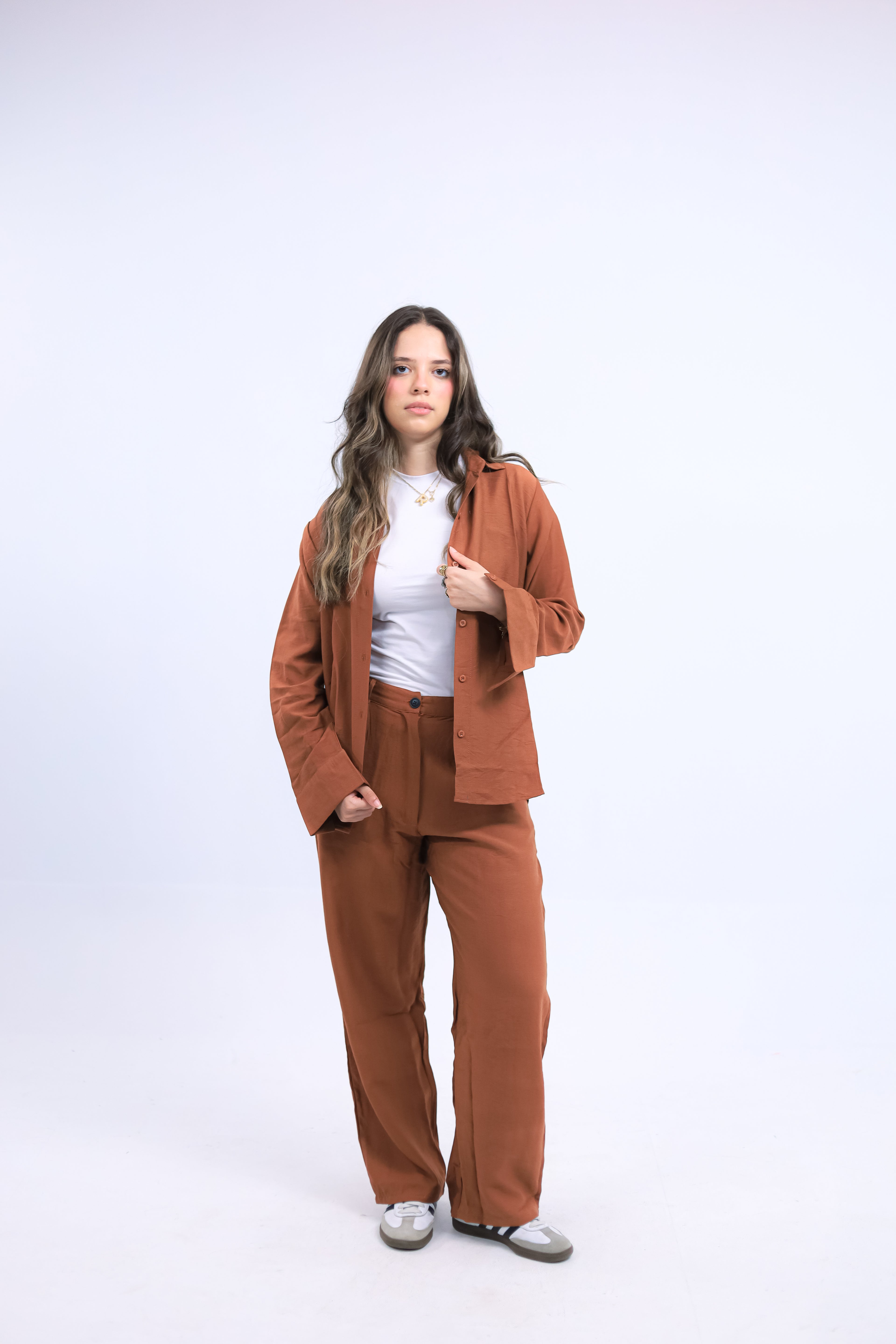 Woman wearing beige linen co-ord set – oversized shirt with wide-leg pants, standing against neutral background